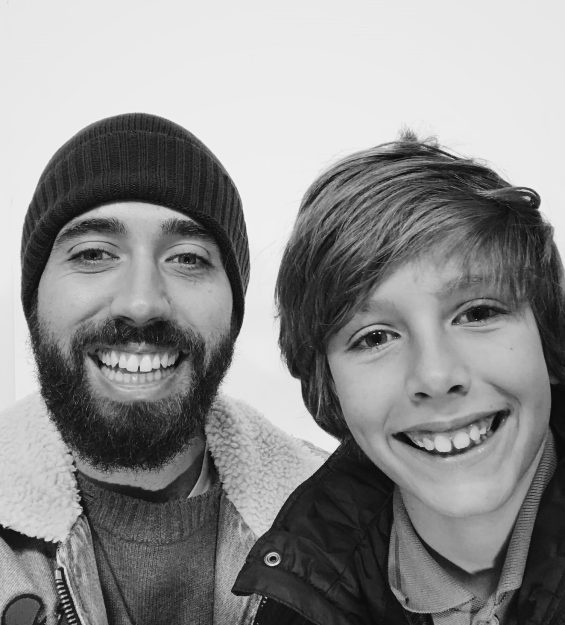 Black and white photograph of a smiling father and son inside a photo booth.