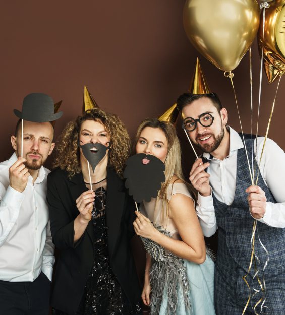 Happy people wearing party hats with photo booth props are celebrating holiday or event