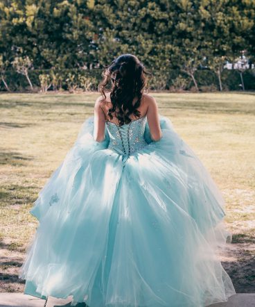 A young lady dressed in her fluffy aqua colored prom dress / quinceanera seen from behind