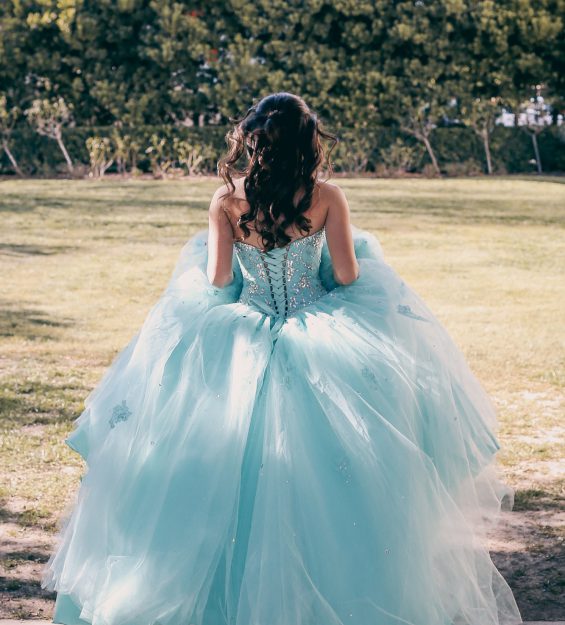 A young lady dressed in her fluffy aqua colored prom dress / quinceanera seen from behind