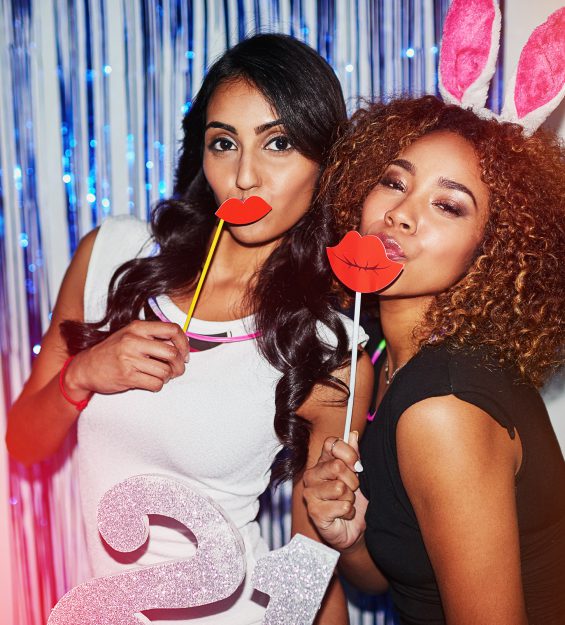 Shot of two beautiful young women having fun with props in a photobooth